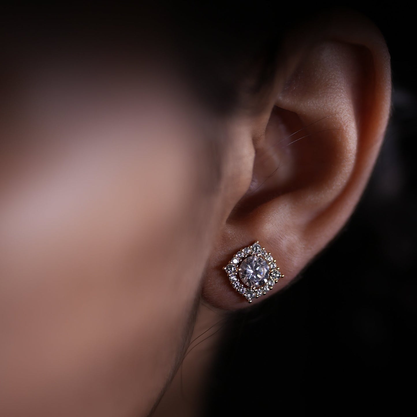 Close-up of an ear wearing a diamond earring with a blurred background