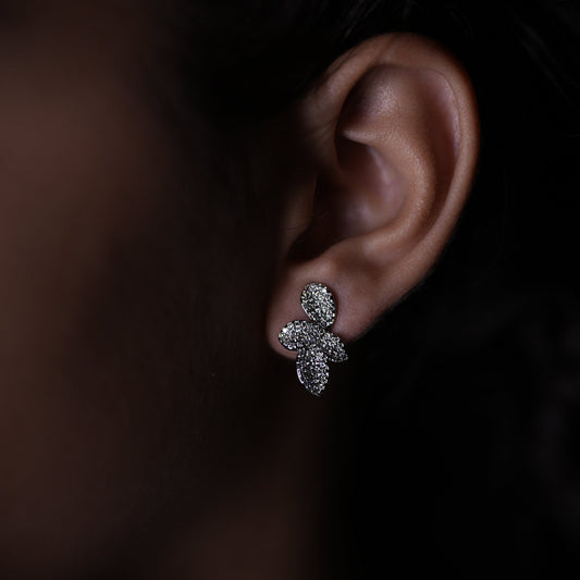 Close-up of an ear wearing a diamond earring against a dark background