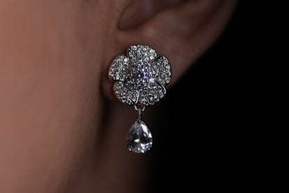 Close-up of a diamond earring worn on an ear against a dark background