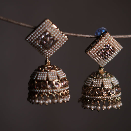 Pair of decorative earrings hanging on a dark background