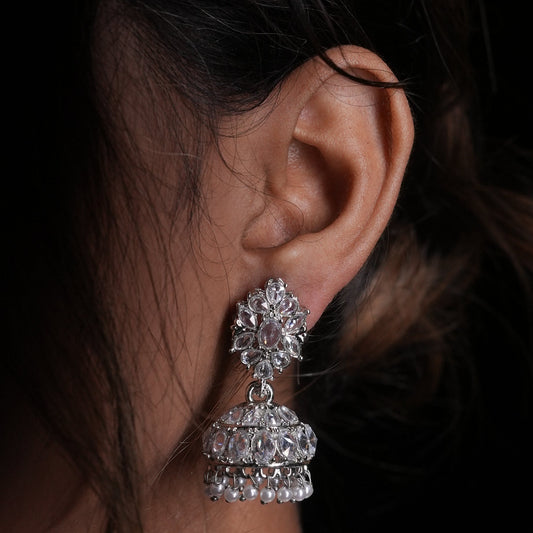 Close-up of an ear wearing a sparkling silver earring with a dark background