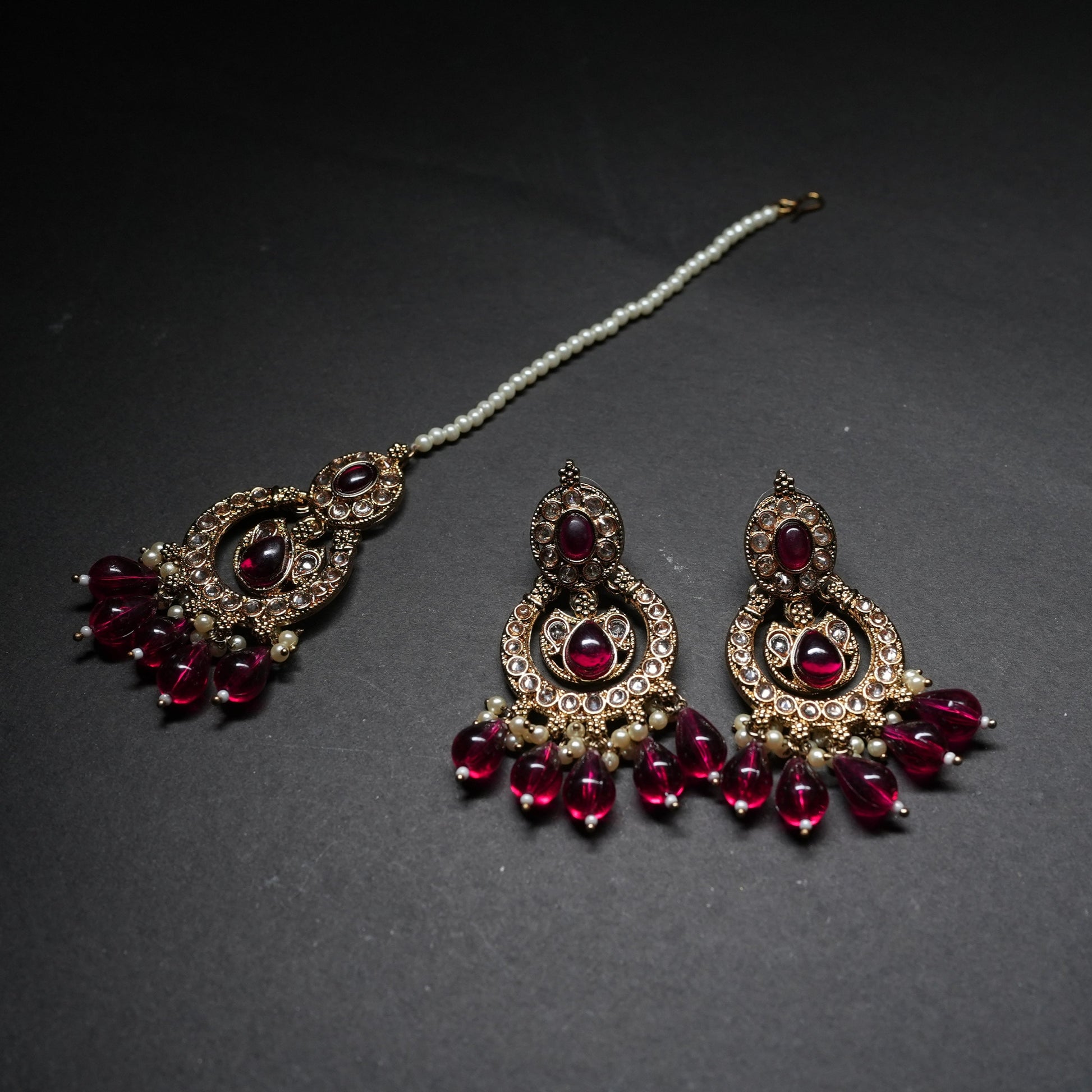 Ornate earrings with red gemstones on a dark background