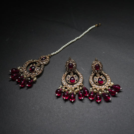 Ornate earrings with red gemstones on a dark background