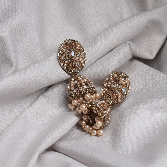 Pair of gold earrings with pearl accents on a light fabric background