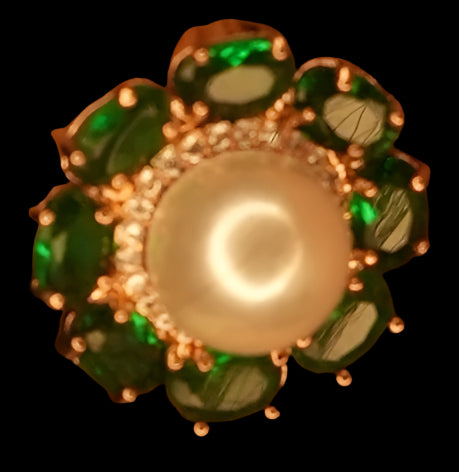 Close-up of an ear wearing a decorative earring with green gemstones.