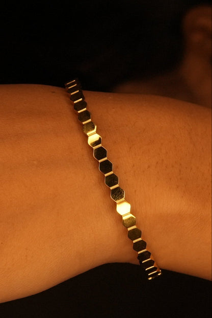Gold bracelet on a wrist with a dark background