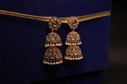 Pair of gold jhumka earrings on a dark blue background
