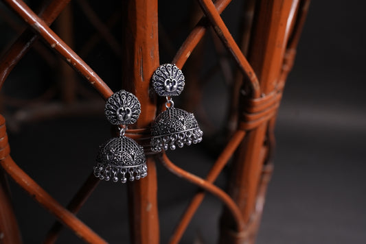Silver earrings on a wicker chair with a dark background